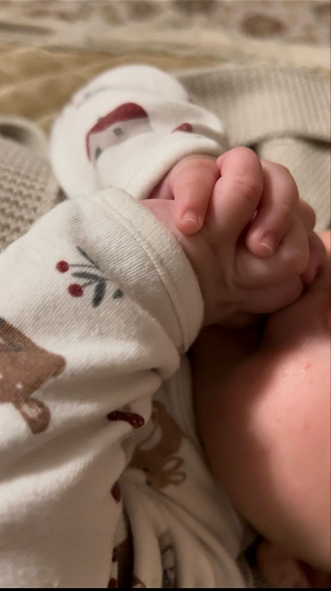 a close up of a baby laying on top of a bed next to a blanket