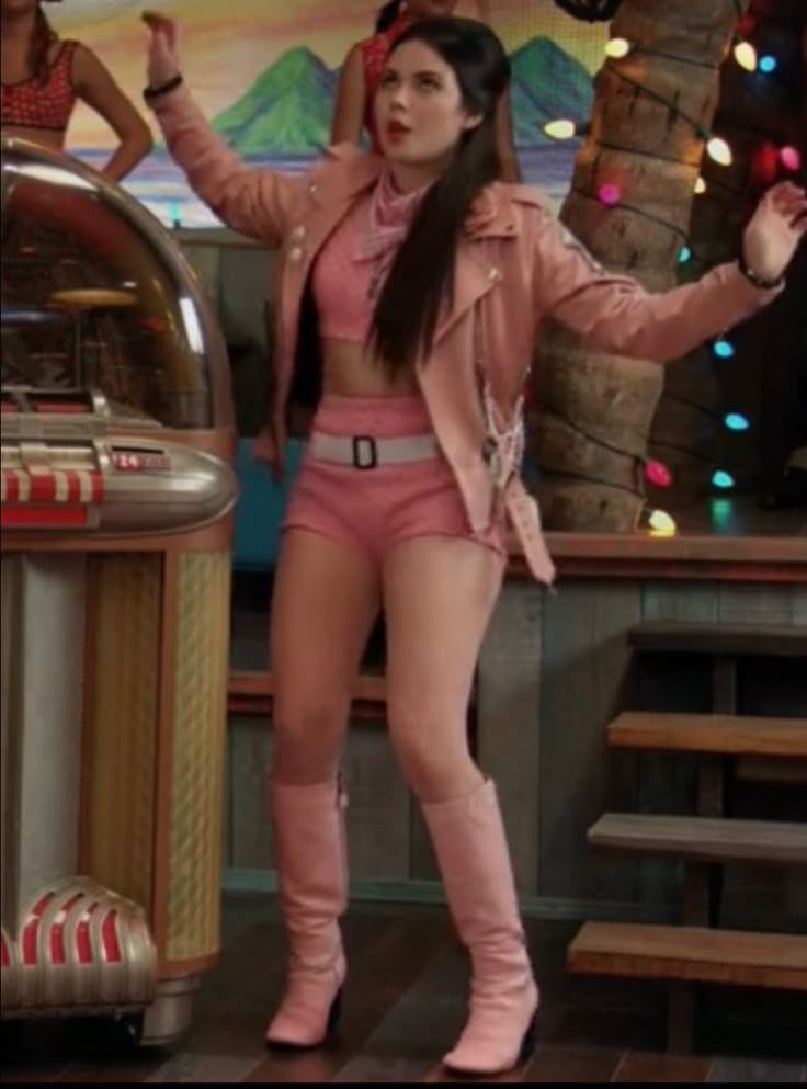 a woman in pink shorts and boots standing next to a jukebox with lights on