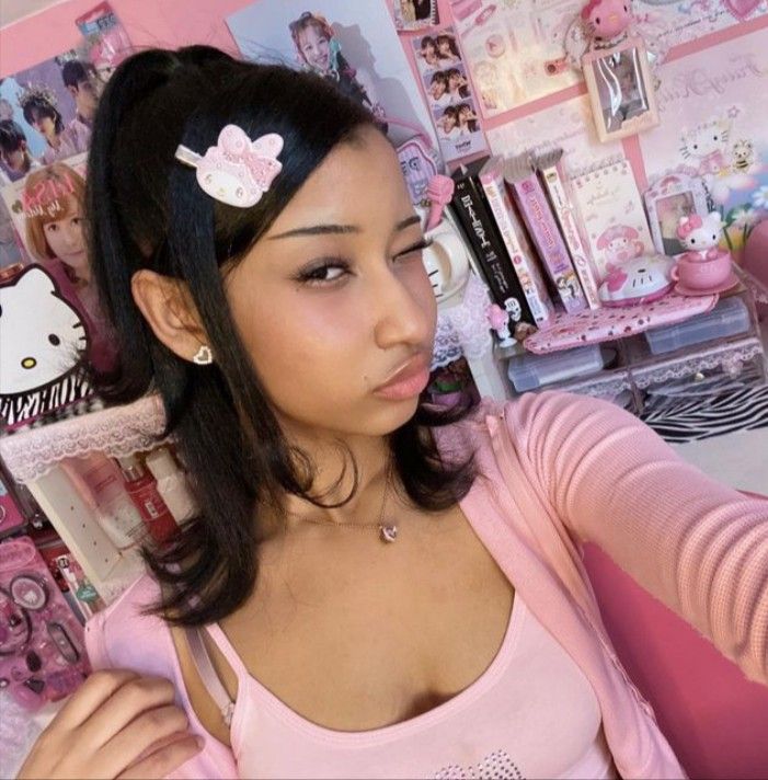 a young woman is taking a selfie in front of a wall with hello kitty pictures on it