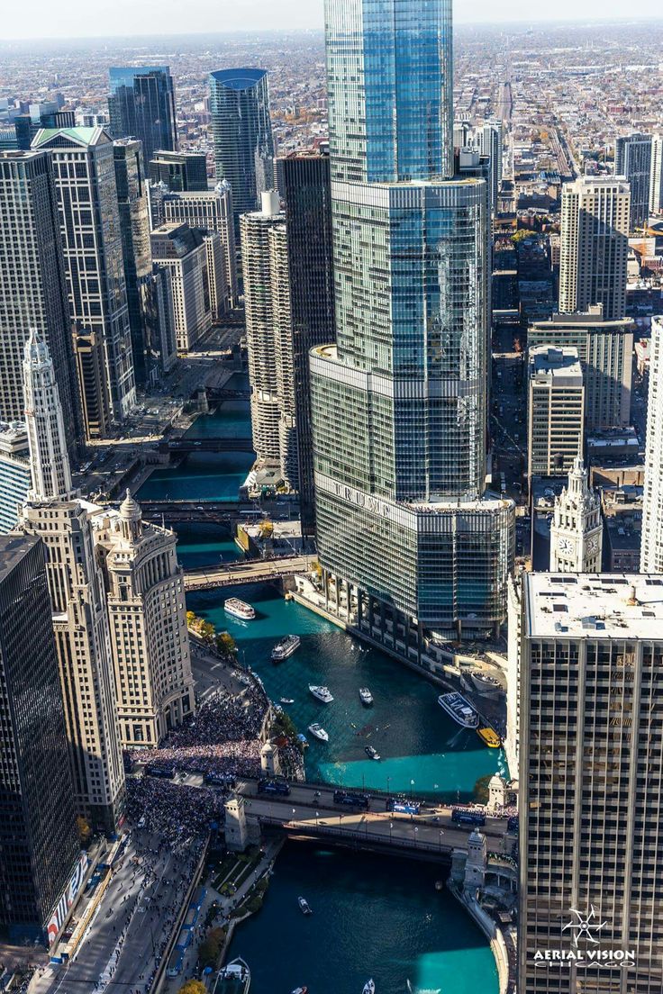 an aerial view of a city with tall buildings and boats on the water in front of them