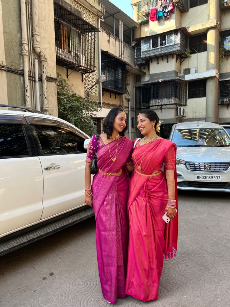 two women standing next to each other in front of a car