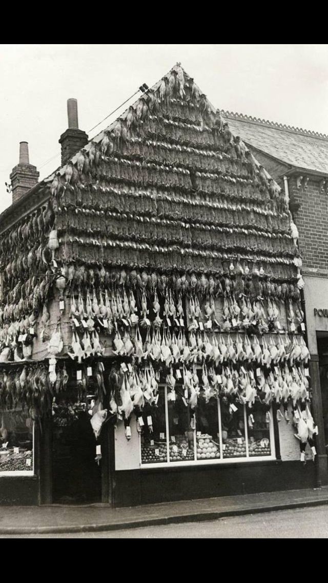 an old black and white photo of the outside of a store with many items on display