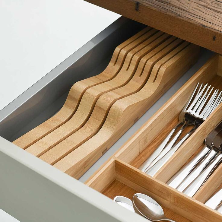 an open drawer with utensils and spoons in it on top of a table