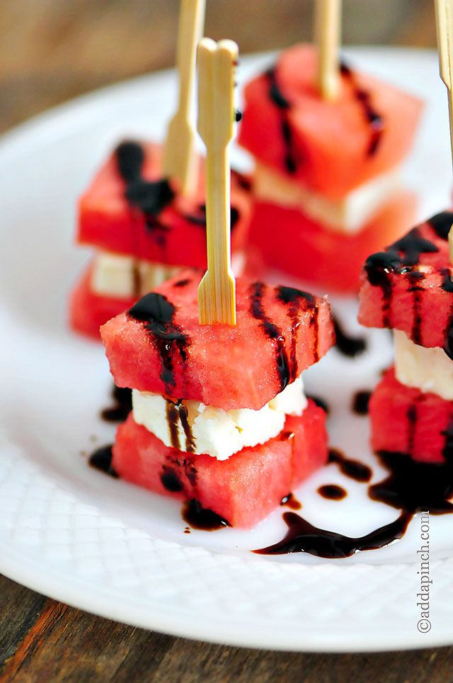 watermelon skewers with chocolate drizzled on them sitting on a white plate