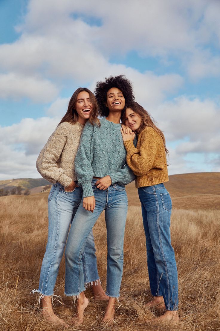 three women are standing in the middle of a field