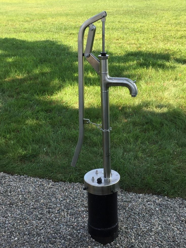 a black and silver fire hydrant sitting on top of a gravel ground next to grass