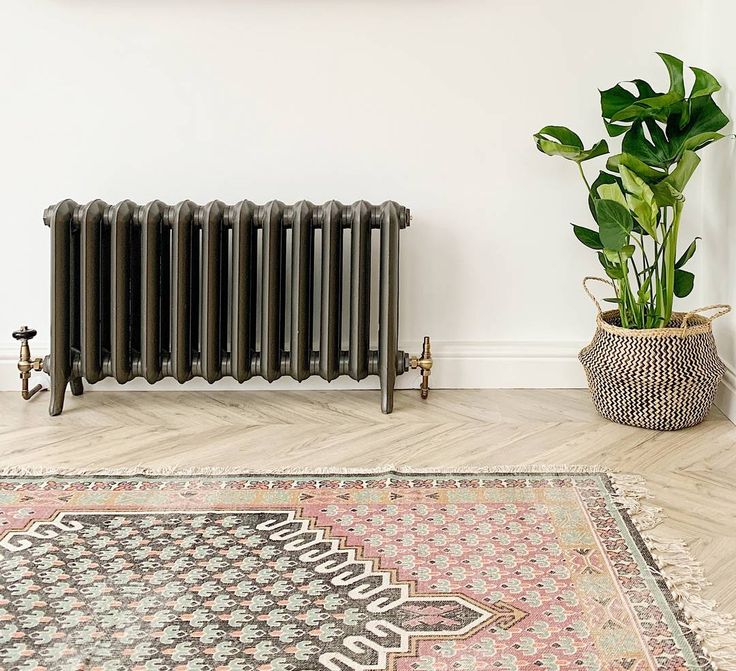 a radiator in the corner of a room next to a potted plant