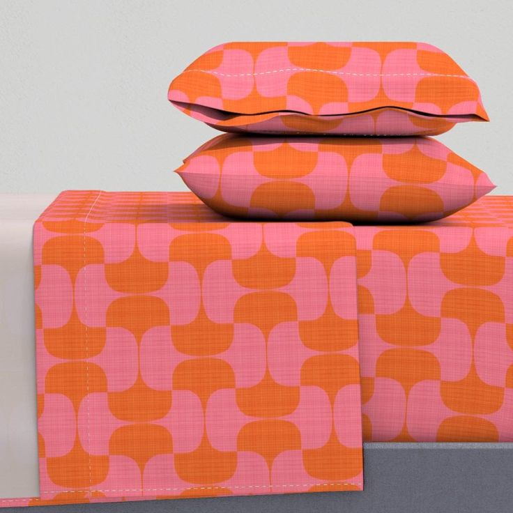 three pillows are stacked on top of each other in an orange and pink print pattern