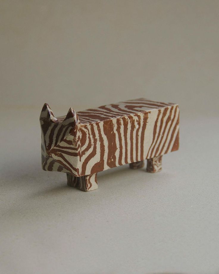 a small wooden animal figurine sitting on top of a white table next to a wall