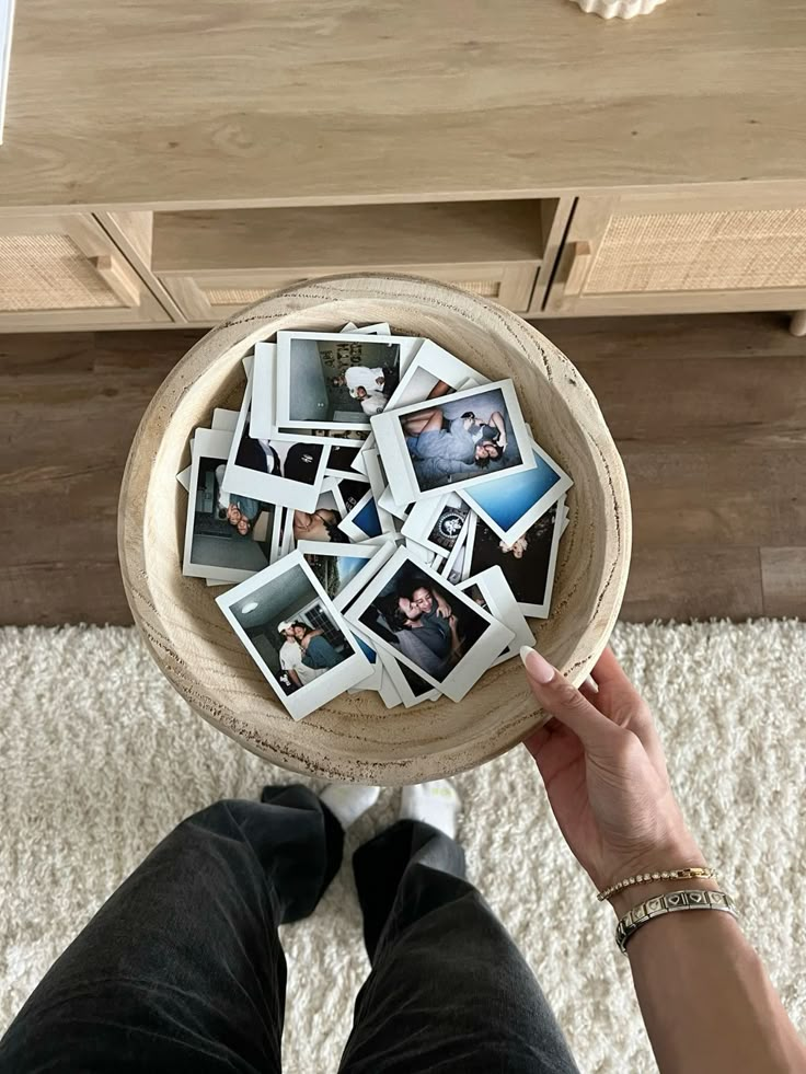 a person is holding a wooden bowl with photos on it in front of a white rug