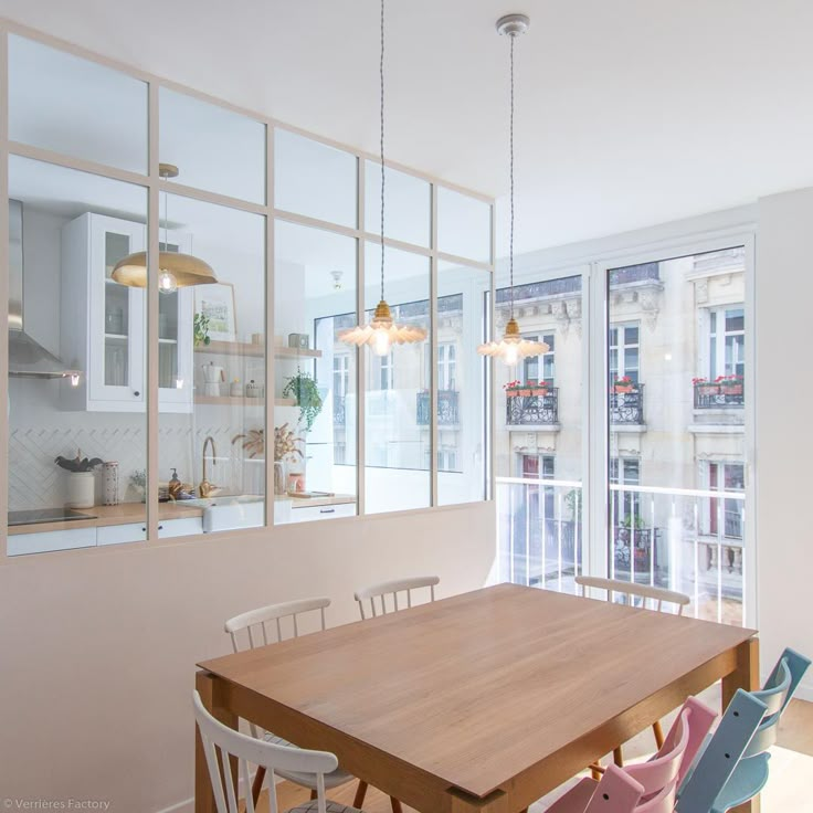 a wooden table sitting in front of a window filled with lots of windows next to a kitchen