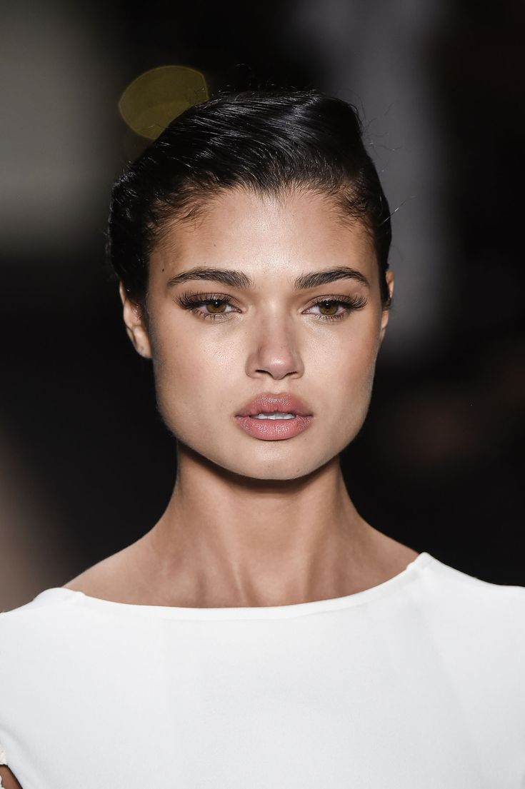 a close up of a person wearing a white shirt and black hair with a crown on her head