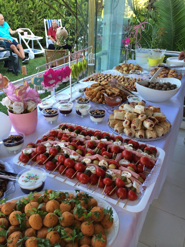 a table filled with lots of food on top of a white tablecloth covered ground