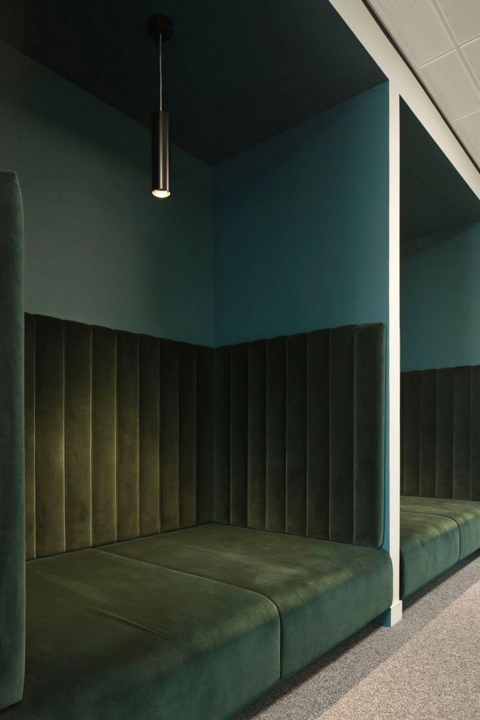 green velvet couches are lined up against the wall in an empty room with blue walls