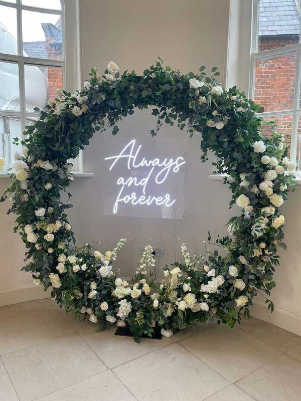 a sign that says always and forever surrounded by white flowers in front of a window