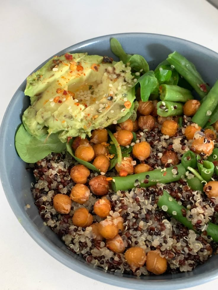 a blue bowl filled with rice, beans and veggies next to an avocado