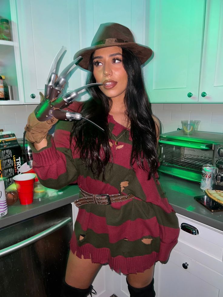 a woman wearing a hat and holding scissors in her hands while posing for the camera