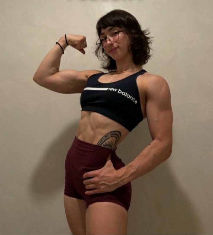 a woman posing for the camera with her arm up and showing off her muscular muscles