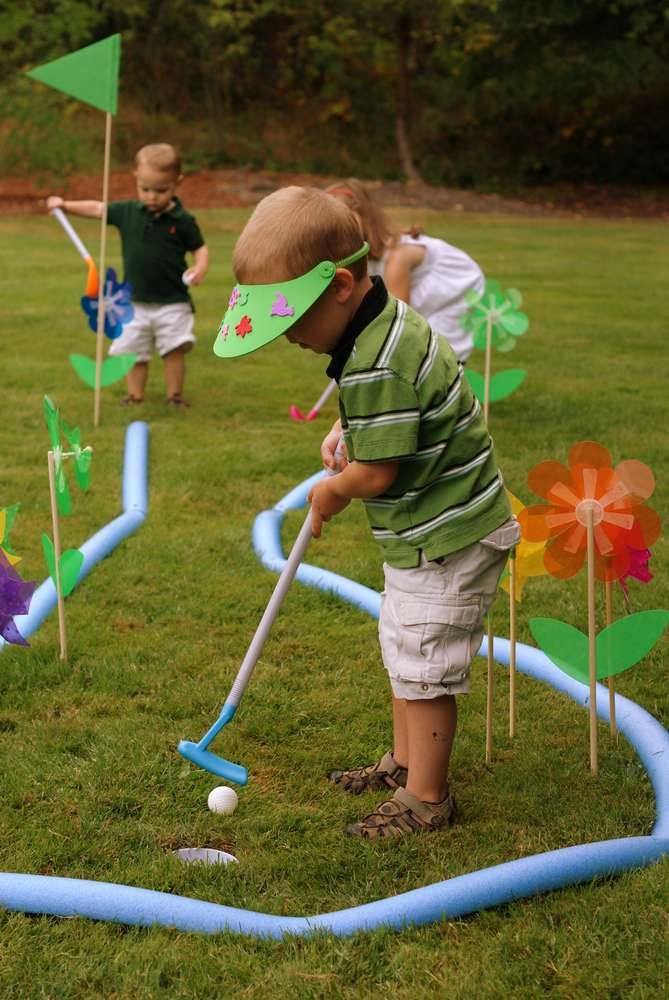 two young boys are playing golf in the yard