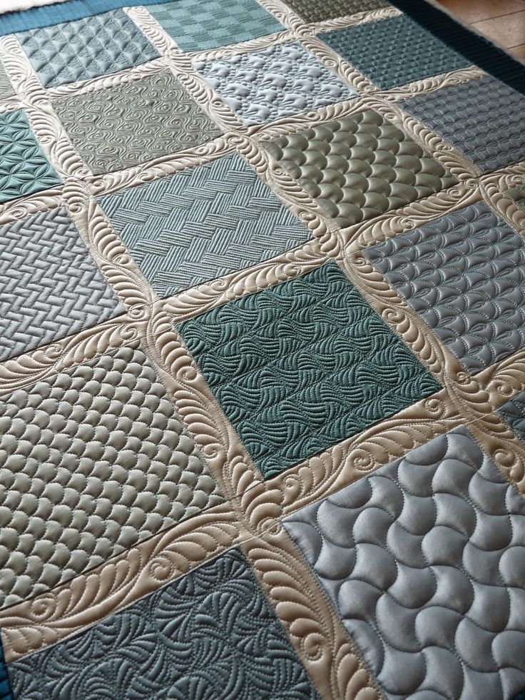 a close up of a quilt on the floor with blue and green squares in it