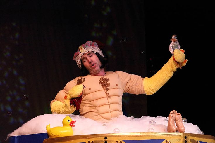 a man in a costume sitting on top of a bath tub holding a stuffed animal