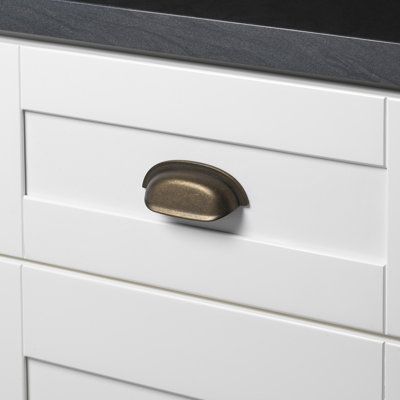 a close up of a drawer with a black counter top and white cabinet drawers in the background