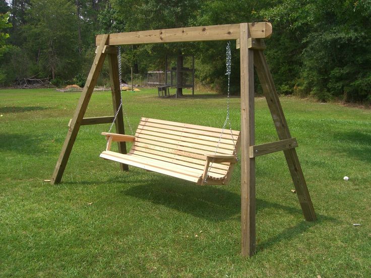 a wooden swing set sitting on top of a lush green field