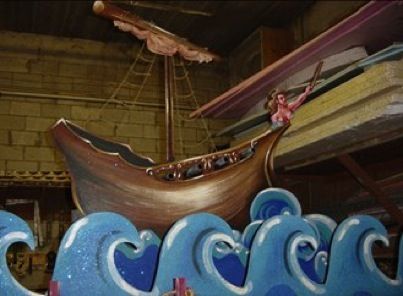 a wooden boat is on display in a museum like setting with blue and white waves