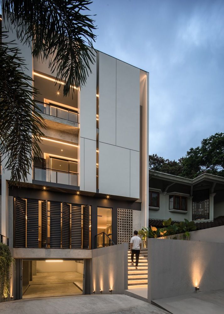 a man is walking up the stairs in front of a modern house at night time