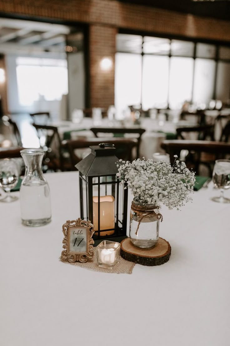 a table topped with a lantern and vases filled with baby's breath flowers