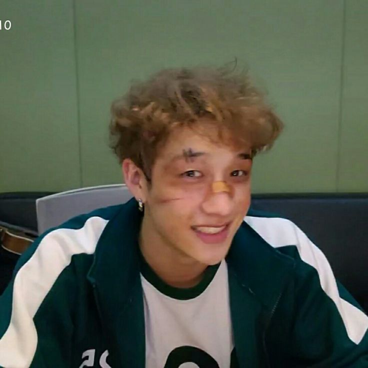 a young man sitting in front of a computer screen with his finger on his nose