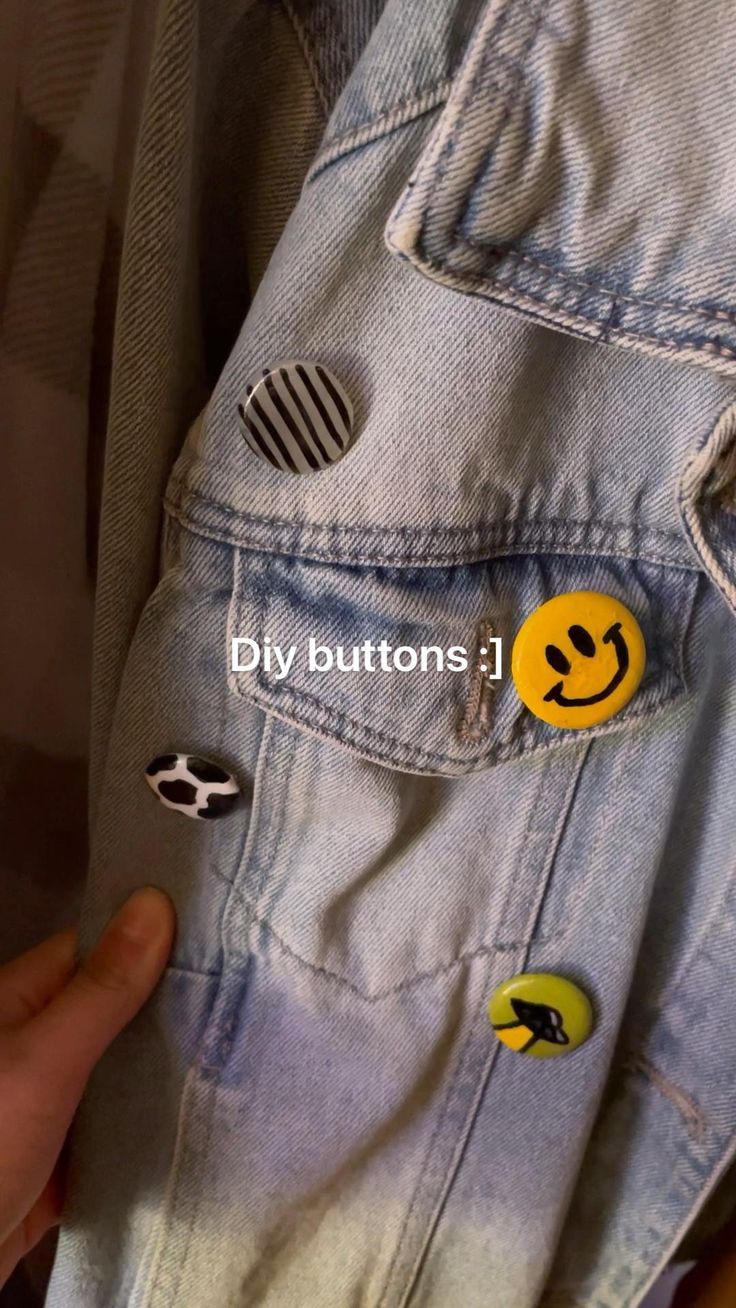 someone is holding their jacket with some smiley face buttons on the back and one hand pointing at it