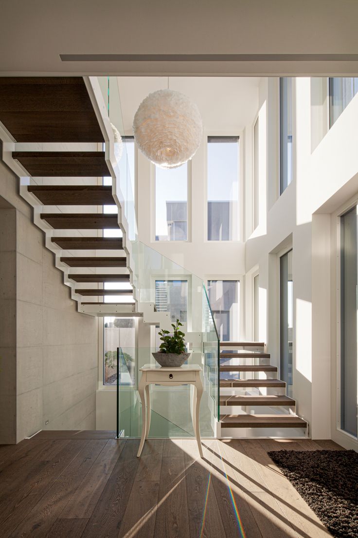 a room with some stairs and a table in front of the window on the far side