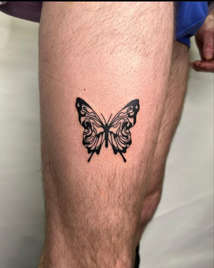 a man's leg with a butterfly tattoo on the side of his calf area