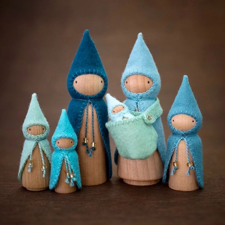 three wooden dolls with blue hats and one is holding a baby