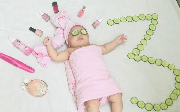 a baby laying on top of a bed next to cosmetics