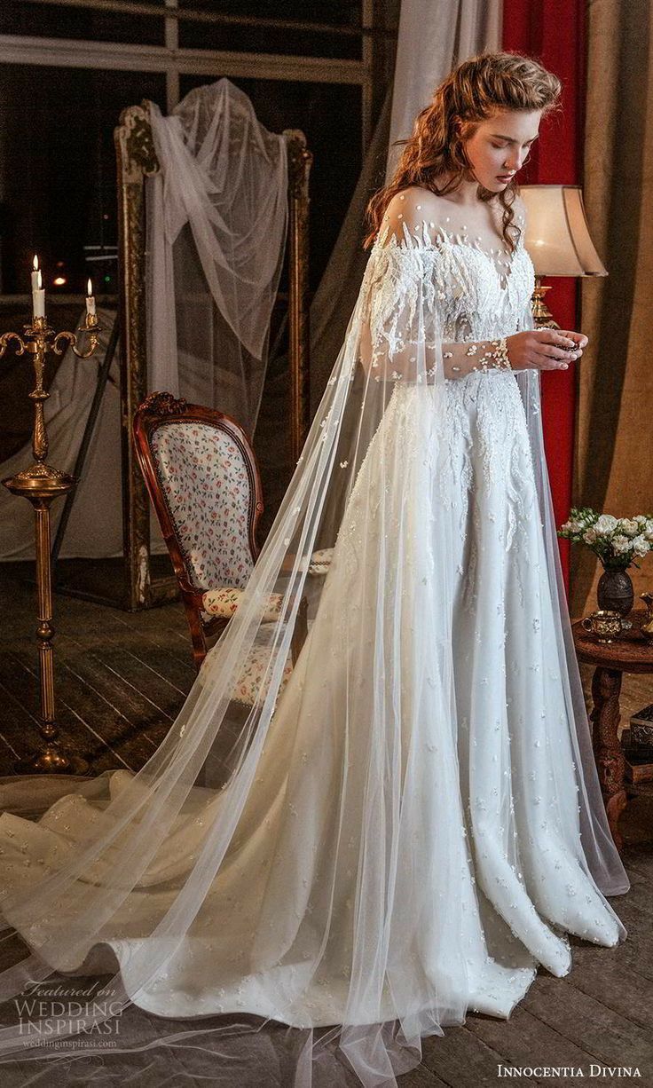 a woman in a white wedding dress standing next to a red chair with a long veil on her head