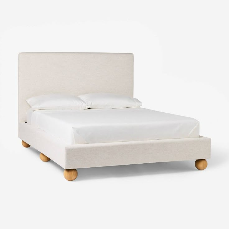 a bed with white linen and wooden legs on the headboard, in front of a white background