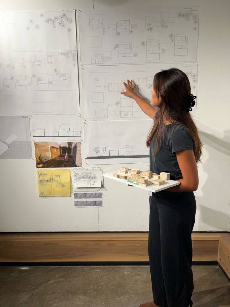 a woman standing in front of a whiteboard holding a tray of doughnuts