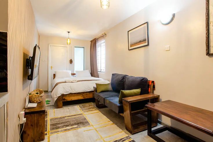 a living room with a couch, coffee table and television in the corner next to a bed