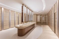 a large bathroom with two sinks and several mirrors on the wall, along with wooden doors