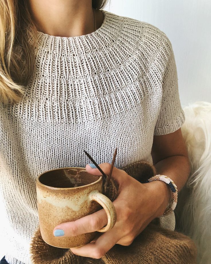 a woman holding a coffee cup with scissors in it