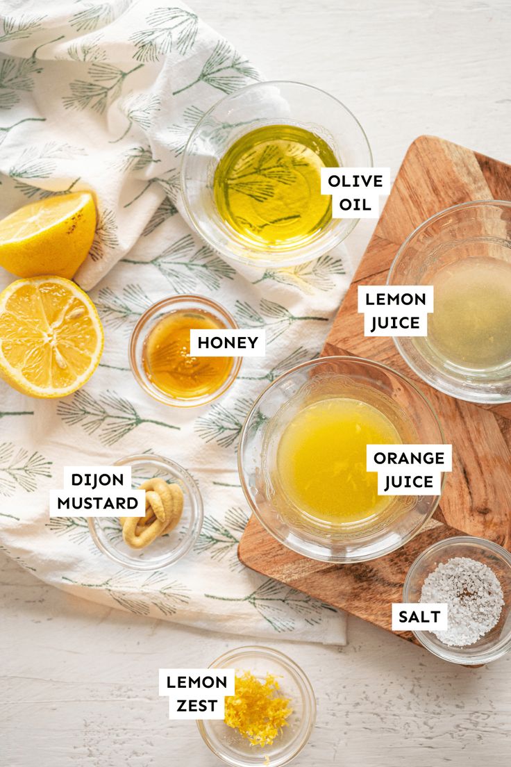 the ingredients to make lemonade are shown on a cutting board, including honey, orange juice, lemon zest, and olive oil