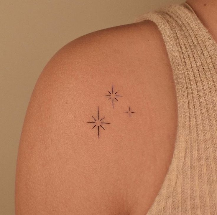 a woman's back shoulder with three stars on the left side of her arm