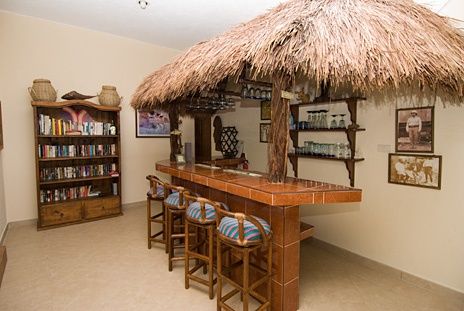 a bar with stools and a straw umbrella over it