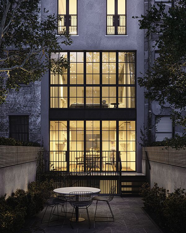 a table and chairs in front of a building at night with the windows lit up