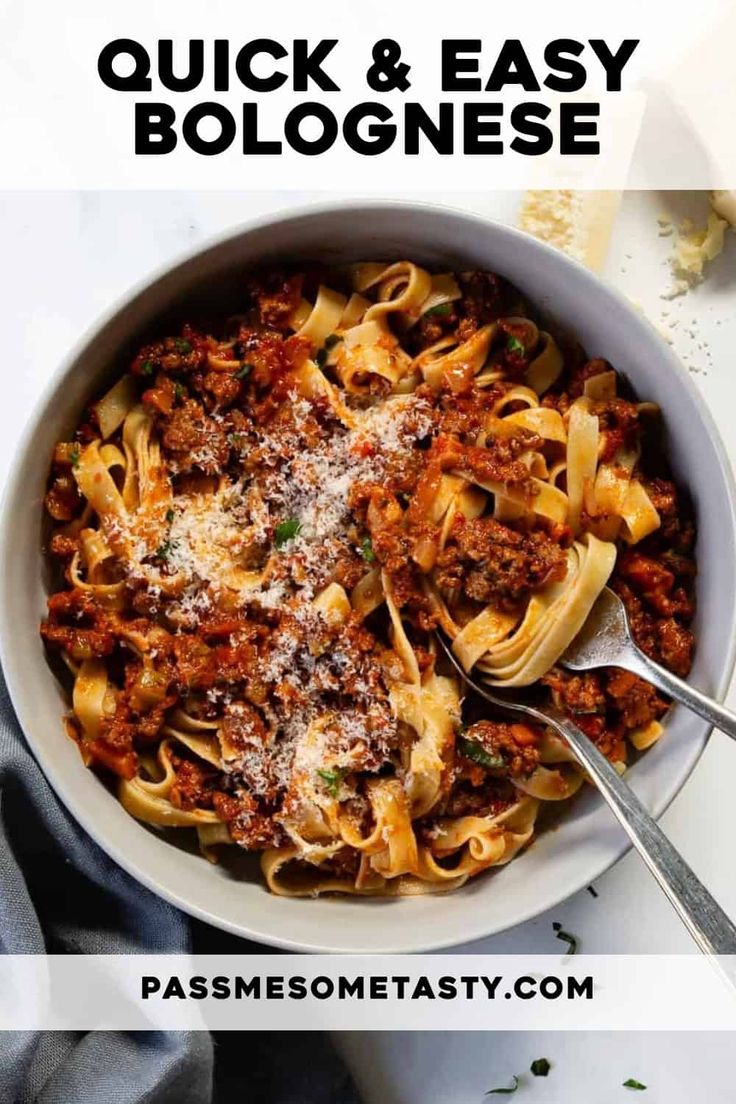 a white bowl filled with pasta and meat sauce on top of a table next to a fork