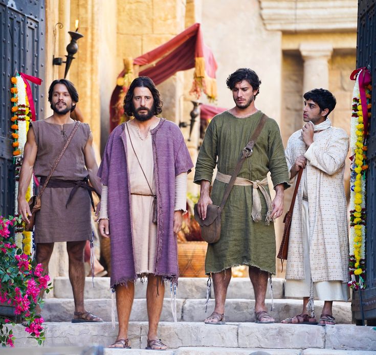 the three men are dressed in roman clothing and standing on steps outside an open doorway