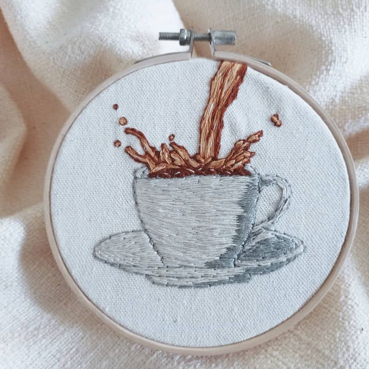 a cup of coffee is being embroidered onto a white cloth