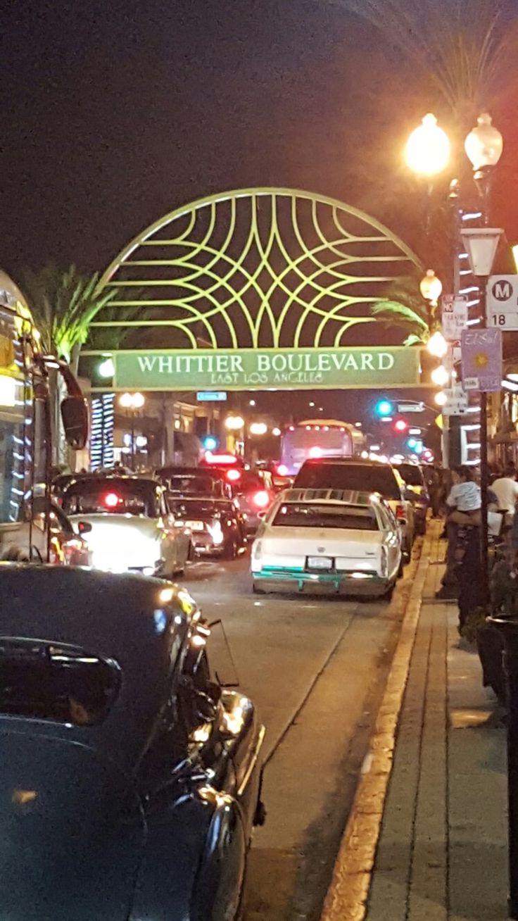 many cars are parked on the side of the road at night in front of a white boulevard sign